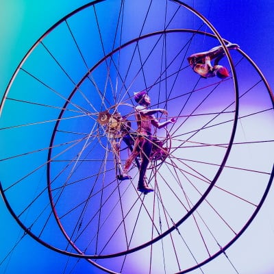 Two performers inside a large aerial wheel.