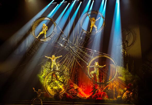 Four performers hang onto a round metallic spinning contraption named the Wheel of Death - Drawn to Life Cirque du Soleil.